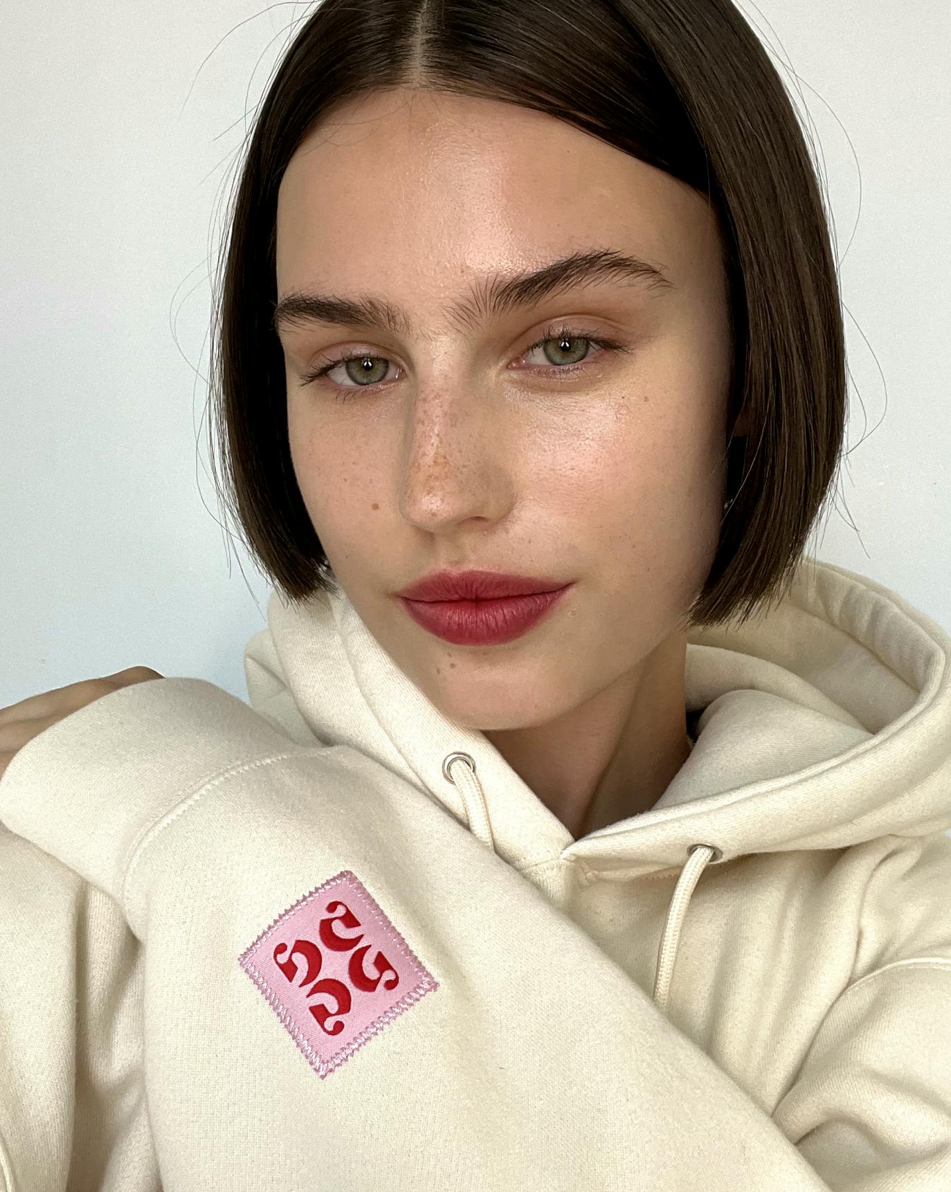 Chloe wears the limited-edition Embroidered Cream Hoodie.
